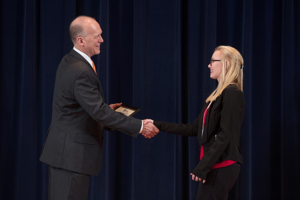 Doctor Potteiger shaking hands with an award recipient in a black blazer and red shirt